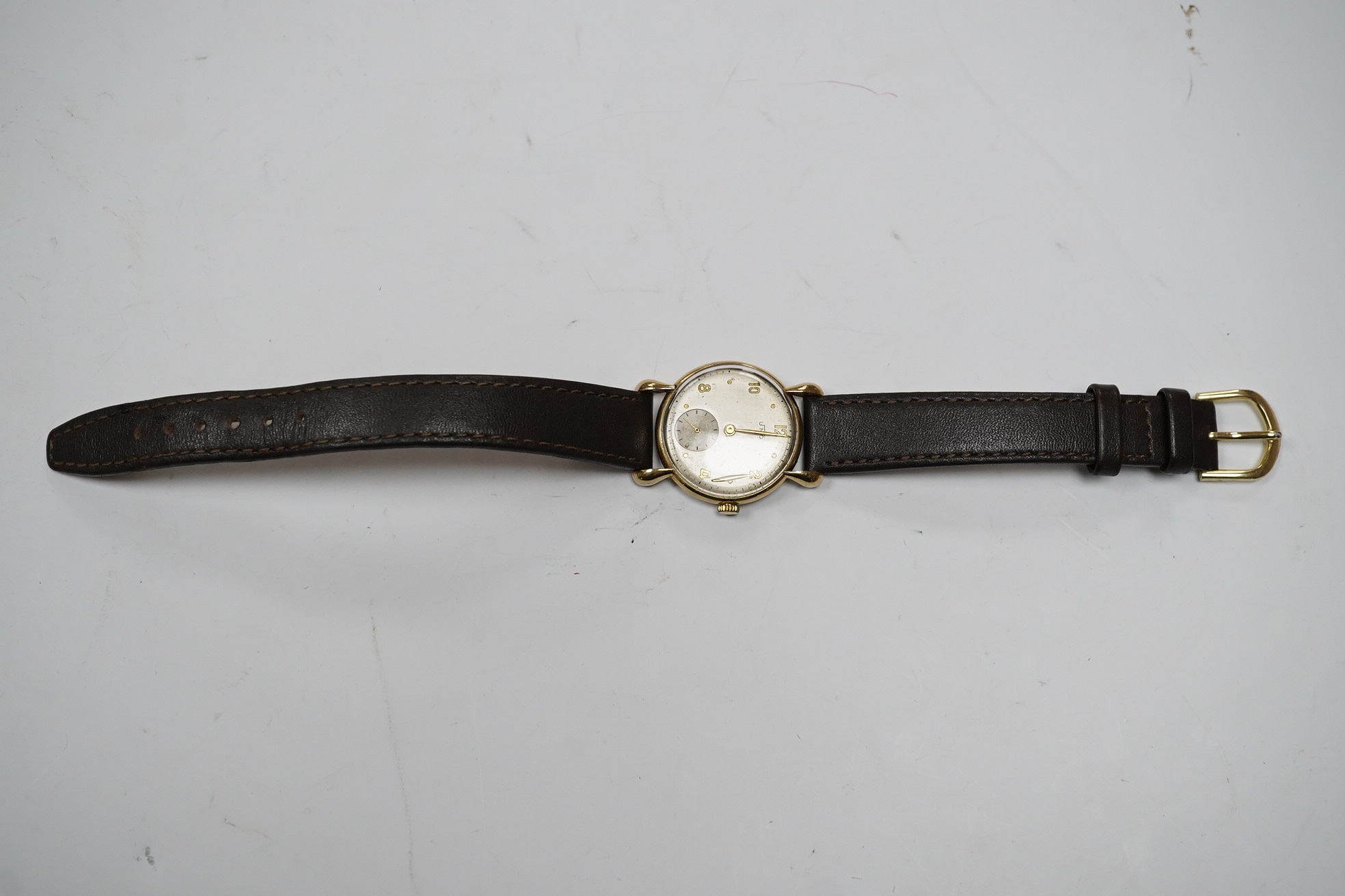 A gentleman's 9ct Uno manual wind wrist watch, with Arabic and dot numerals, with subsidiary seconds, case diameter 29mm, on a leather strap. Condition - poor.